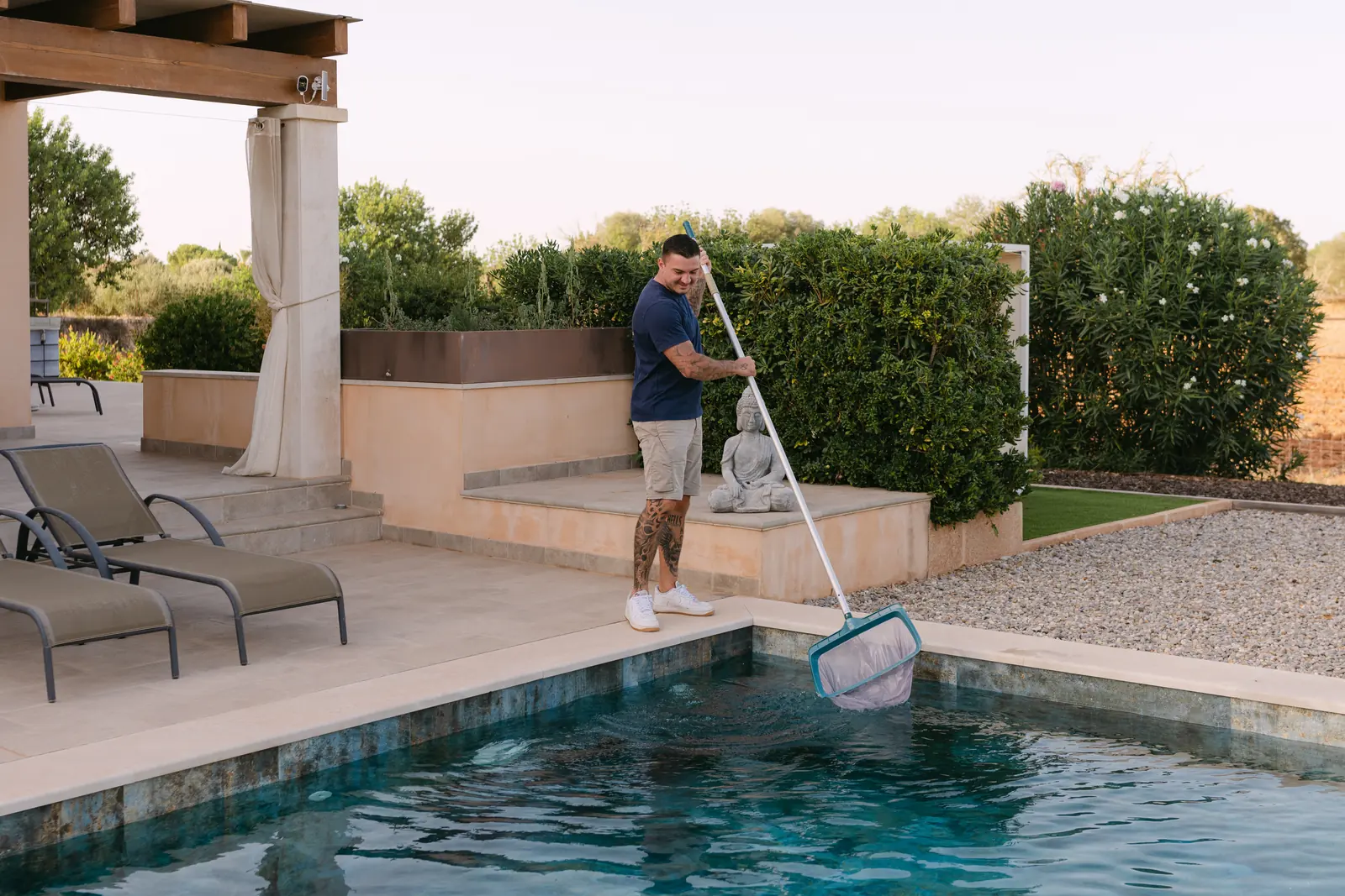 Cleaning a pool with the skimmer net at the edge of a finca pool